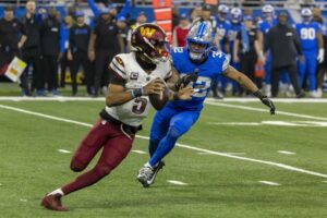 Jan 18, 2025; Detroit, Michigan, USA; Washington Commanders quarterback Jayden Daniels (5) looks to pass defended by Detroit Lions defensive back Brian Branch (32) during the second half at Ford Field.