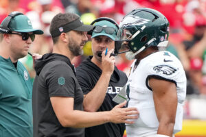 Sep 14, 2025; Kansas City, Missouri, USA; Philadelphia Eagles head coach Nick Sirianni and offenisve coordinator Kevin Patullo speak with Philadelphia Eagles quarterback Jalen Hurts (1) during the second quarter of the game against the Kansas City Chiefs at GEHA Field at Arrowhead Stadium.