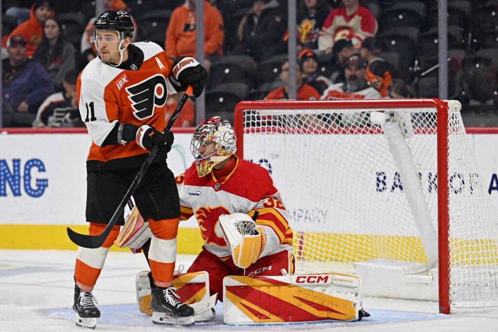 Nov 2, 2025; Philadelphia, Pennsylvania, USA; Philadelphia Flyers right wing Travis Konecny (11) battles for position against Calgary Flames goaltender Dustin Wolf (32) during the second period at Xfinity Mobile Arena.