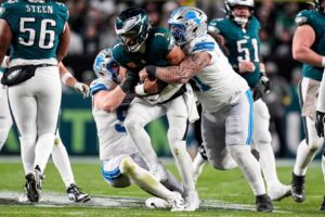 Detroit Lions defensive tackle Roy Lopez (51), right, and defensive end Aidan Hutchinson (97) tackle Philadelphia Eagles quarterback Jalen Hurts (1) during the second half at Lincoln Financial Field in Philadelphia on Sunday, November 16, 2025.
