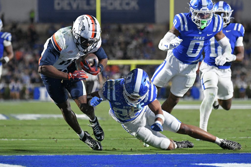 Nov 15, 2025; Durham, North Carolina, USA; Virginia Cavaliers wide receiver Trell Harris (11) takes a hit from Duke Blue Devils saftey Ma'khi Jones (26) during the third quarter at Wallace Wade Stadium.