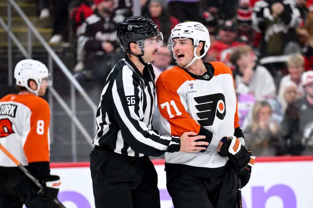 Nov 29, 2025; Newark, New Jersey, USA; Philadelphia Flyers right wing Tyson Foerster (71) is restrained by linesman Julien Fournier (56) during the third period against the New Jersey Devils at Prudential Center.