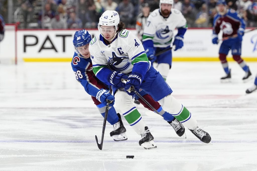 Dec 2, 2025; Denver, Colorado, USA; Colorado Avalanche center Martin Necas (88) defends on Vancouver Canucks defenseman Quinn Hughes (43) during the second period at Ball Arena.