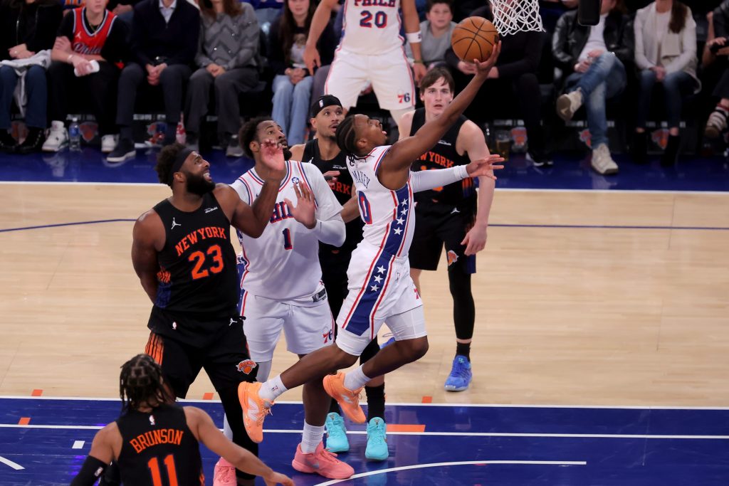 Dec 19, 2025; New York, New York, USA; Philadelphia 76ers guard Tyrese Maxey (0) drives to the basket against New York Knicks guard Jalen Brunson (11) and center Mitchell Robinson (23) and guards Josh Hart (3) and Tyler Kolek (13) during the fourth quarter at Madison Square Garden.
