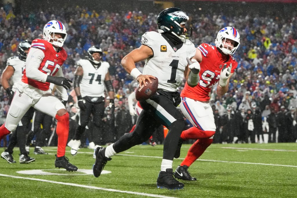 Dec 28, 2025; Orchard Park, New York, USA; Philadelphia Eagles quarterback Jalen Hurts (1) scrambles against Buffalo Bills defensive ends Joey Bosa (97) and Greg Rousseau (50) during the third quarter at Highmark Stadium.