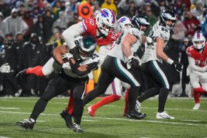 Dec 28, 2025; Orchard Park, New York, USA; Buffalo Bills defensive end Greg Rousseau (50) leaps onto the back of Philadelphia Eagles running back Saquon Barkley (26) to make a tackle during the third quarter at Highmark Stadium.