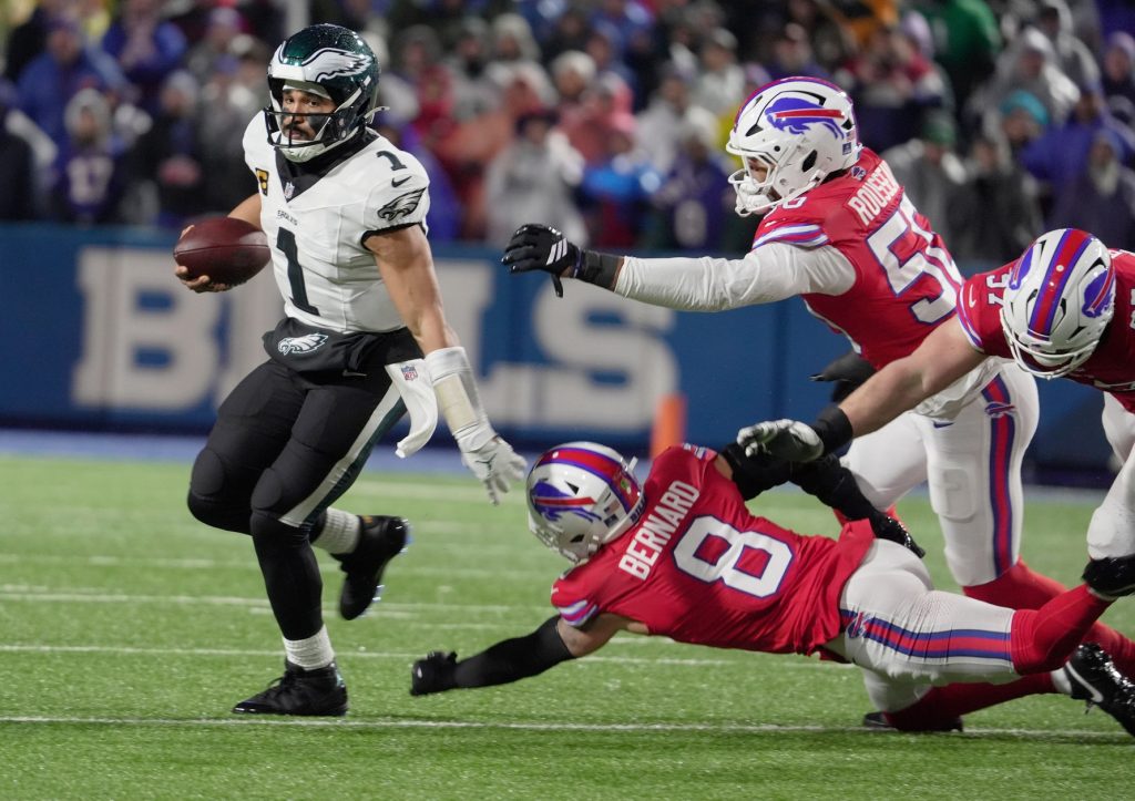 Philadelphia Eagles quarterback Jalen Hurts avoids Buffalo Bills linebacker Terrel Bernard, defensive end Greg Rousseau and defensive end Joey Bosa, who were all trying to sack him during first half action against the Philadelphia Eagles at Highmark Stadium in Orchard Park on Dec. 28, 2025.