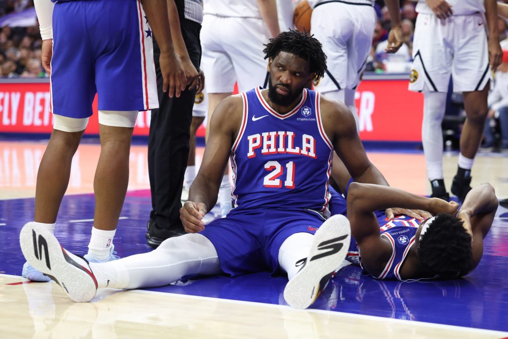 Jan 5, 2026; Philadelphia, Pennsylvania, USA; Philadelphia 76ers center Joel Embiid (21) looks on after falling to the court with guard Vj Edgecombe (77) during the fourth quarter against the Denver Nuggets at Xfinity Mobile Arena.