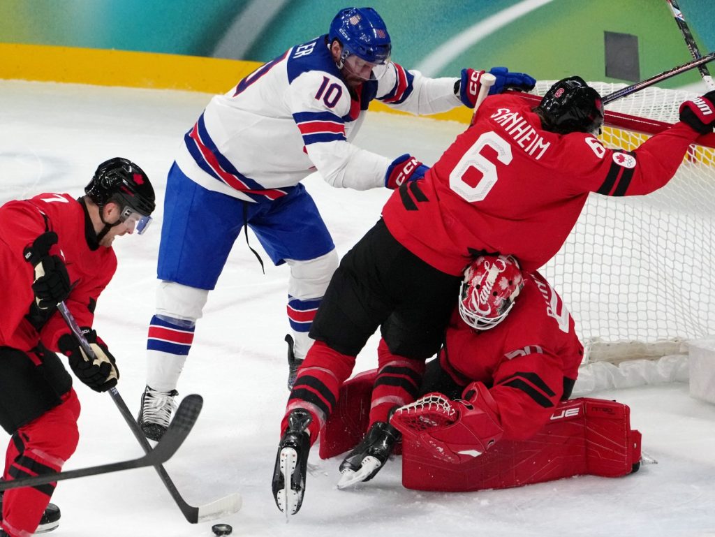 Feb 22, 2026; Milan, Italy; JT Miller of the United States pushes Travis Sanheim of Canada as Devon Toews and Jordan Binnington of Canada reaches for the puck during the men's ice hockey gold medal game during the Milano Cortina 2026 Olympic Winter Games at Milano Santagiulia Ice Hockey Arena.